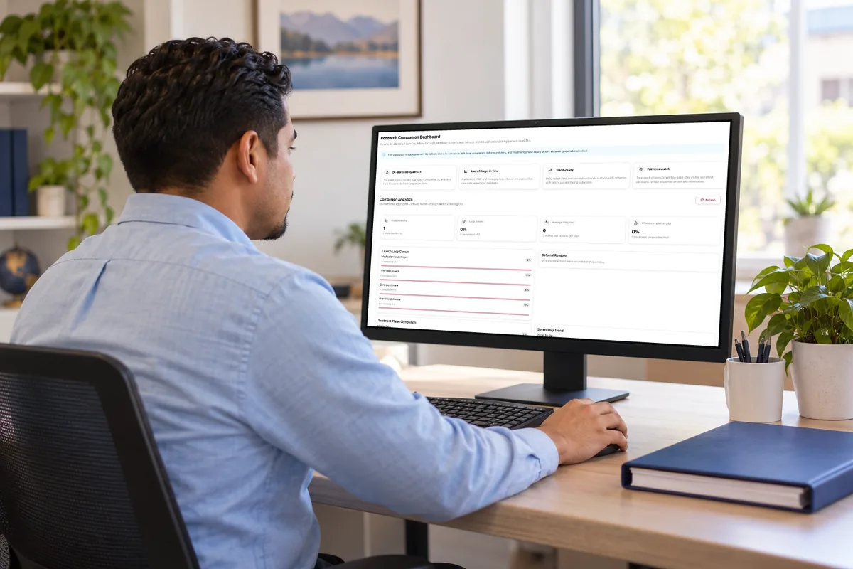 A clinical research coordinator at a desk reads the MyBC research dashboard, an aggregate, de-identified view, on his computer screen.